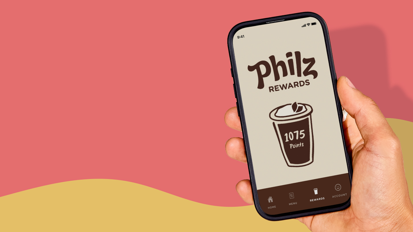 a hand holding a mobile phone featuring the new philz rewards logo