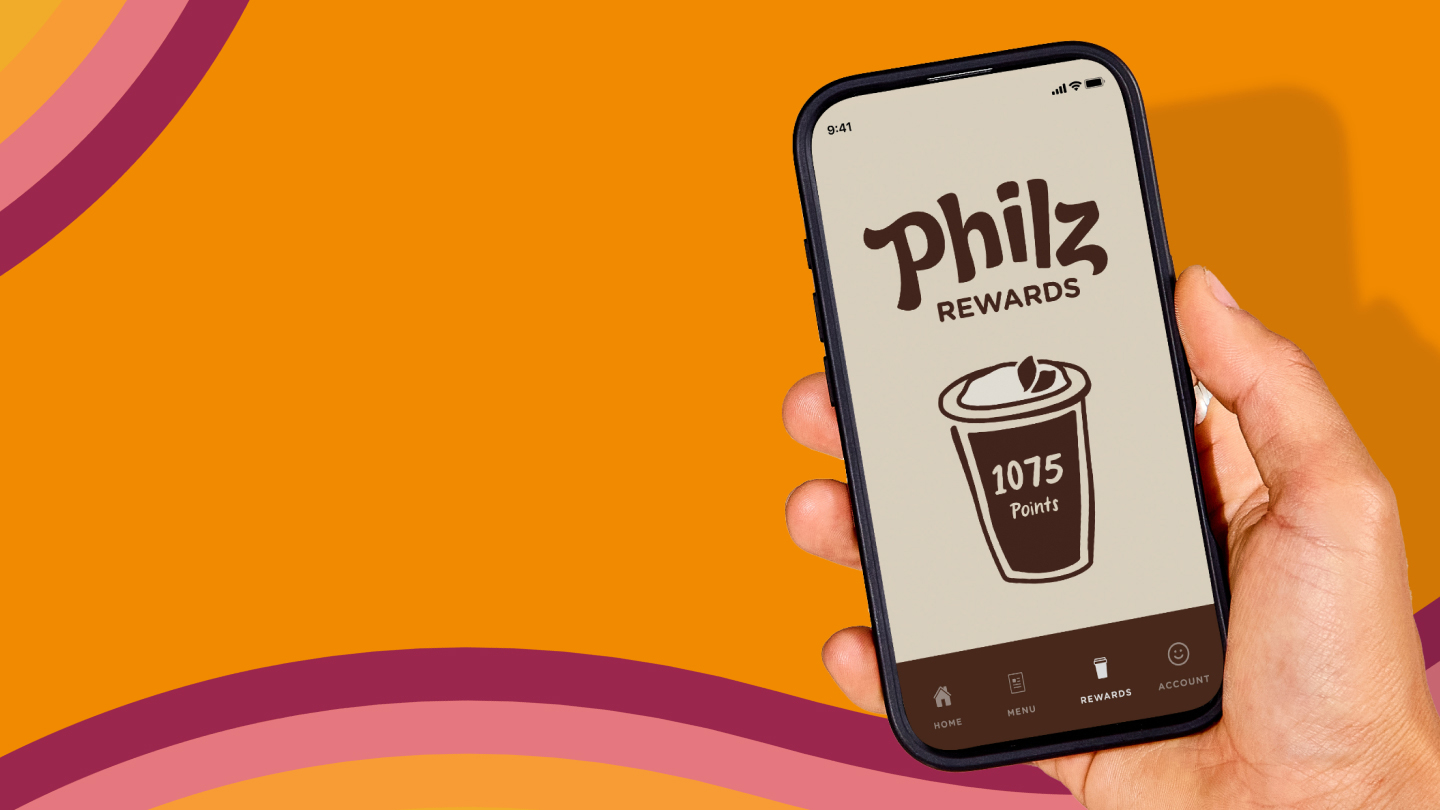 a hand holding a mobile phone featuring the new philz rewards logo